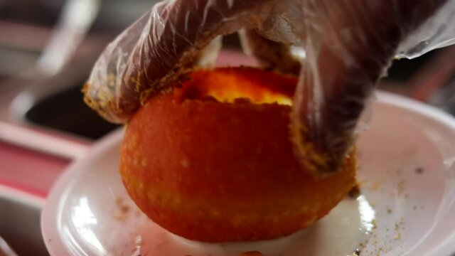 Making indian style street chaat and raj kachori with topped spices, red sauce and corns. 