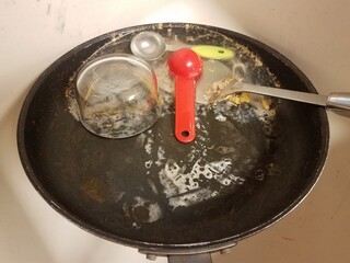 dirty greasy skillet with water in kitchen sink