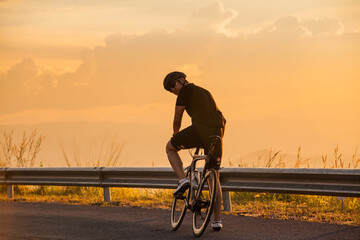 Fototapeta na wymiar Man standing with bicycle Background sunset
