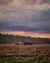 Fototapeta premium Red Tractor in Field at Sunset