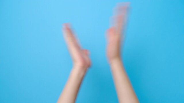 Close up of female hands clapping applause isolated on blue studio background with copy space for advertisement. With place for text or image. Body language concept.