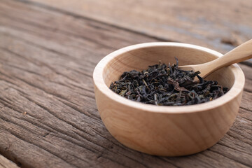 Chinese leaf tea in a wood bowl on grained wood background