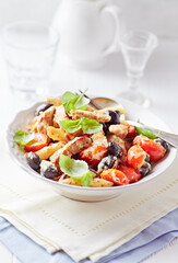 Penne pasta baked with pork tenderloin, cherry tomatoes, black olives and cheese