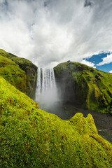 Fototapeta premium Beautiful and powerful of streaming at Skogarfoss waterfall and orange sunlight cover green field around waterfall in evening,Summer,Iceland.