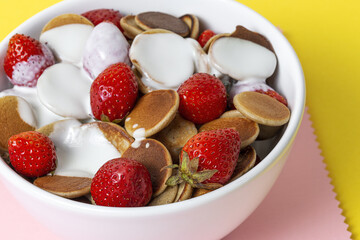 Homemade cereals mini pancake with yogurt, honey and strawberries on colorful background.