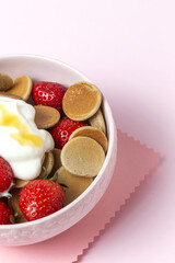 Homemade cereals mini pancake with yogurt, honey and strawberries on colorful background.