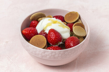 Homemade cereals mini pancake with yogurt, honey and strawberries on colorful background.