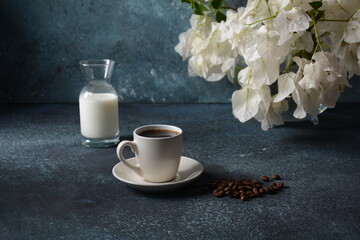Fototapeta na wymiar Composition with white cup of coffee , beans and flowers as background