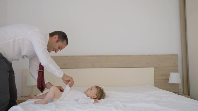 Elegant man changing baby child diaper, business man with tie in parental role, gender work