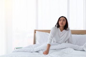 Obraz premium Young girl stretching in bed after wake up. Portrait of beautiful asian woman enjoying fresh soft bed linen mattress in bedroom. Woman Stretching in Her Bed. A Girl waking up in the Morning on bed.