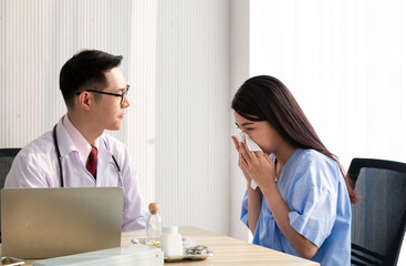 Fototapeta premium Female Patient Being Reassured by Doctor. Young patient visiting doctor in hospital. Close up of doctor and patient sitting at the desk near the window. Male doctor working with female patient. 