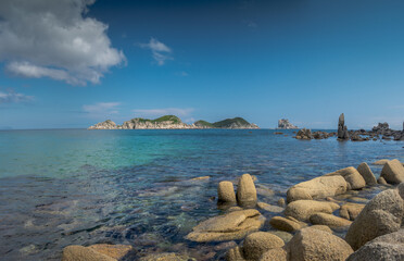 Sea shore with a transparent bottom and small rocky islands in the distance