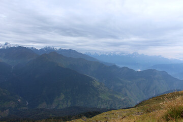 a landscape view of valley and the snow peaked mountains of lower Himalayan range.