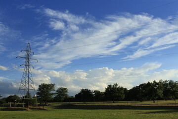 Fototapeta na wymiar high voltage power line with blue sky, grass, and white clouds in Kansas.