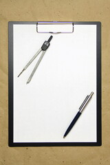 A tablet with a white sheet of A4 format on a beige craft paper with pen and divider. Concept of accurate measurements, study and construction. Stock photo with empty place for your text and design.