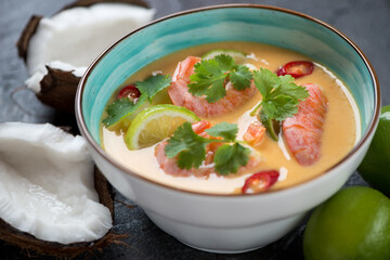 Thai soup with prawns, pumpkin, coconut milk, lime, red chili and coriander served in a turquoise bowl, closeup