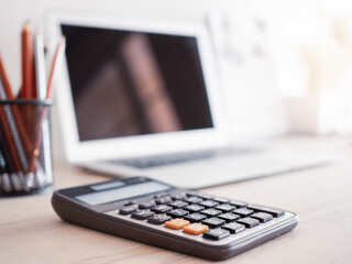 Close up calculator blurred laptop background on table.