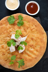 Above view of ossetian pie with potato, chicken, fresh cilantro and dips, closeup, vertical shot