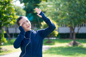 Portrait of Asian woman was sick with headache at park listening to music.