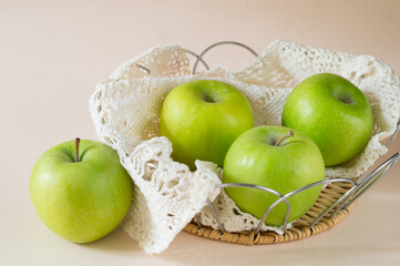 Fresh green apples in a basket with a lace napkin