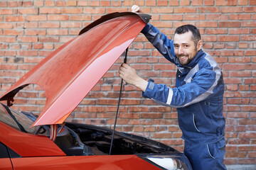 Car service worker near the car. Car service worker smiles at the camera.