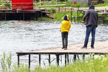 Father teaching his son fishing. concept of father's day. Father and son in yellow jacket fishing together