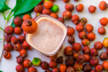 Drink and fruits of red araçá (Psidium cattleyanum) on clear surface
