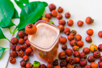 Drink and fruits of red araçá (Psidium cattleyanum) on clear surface