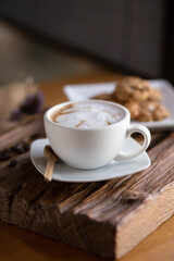 Cappuccino coffee on wood in the morning with cookies on dish at cafe,selective focus.