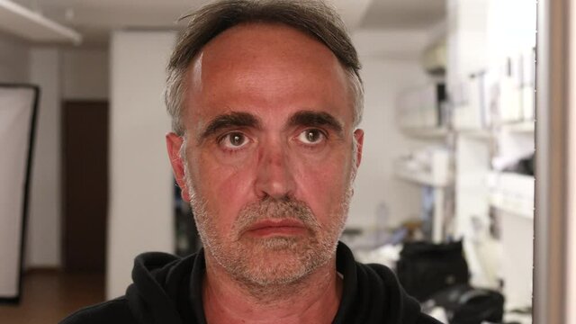 uomo cinquantenne cammina nel suo ufficio rivolto verso la finestra con aria seria