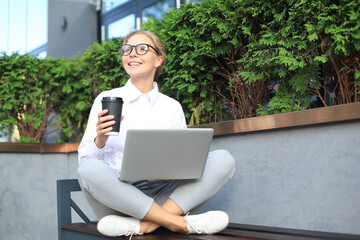 Beautiful business woman sitting near business center and using laptop.