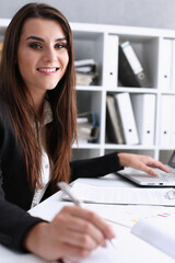 Female hand holding silver pen ready to make note in opened notebook sheet. Businesswoman in suit...