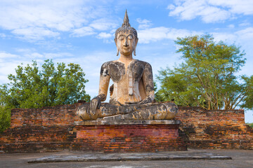 Fototapeta premium Ancient sculpture of a sitting Buddha on the ruins of the Buddhist temple Wat Mae Chon. Sukhothai Historical Park, Thailand