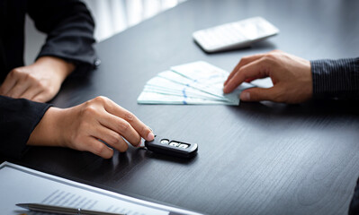 Fototapeta premium Asian woman handed a car key to a male client in the office.