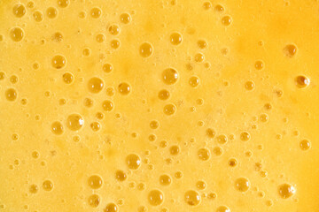 Full frame Yellow foam texture with bubbles of mango and banana fruit smoothie with juice
