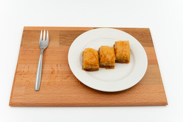 Turkish baklava platter and fork on wooden table on isolated white background.