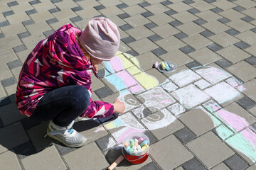 Little girl draw with chalk on the pavement