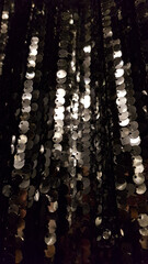 Rows of shining surface with silver sequins on blurred black background