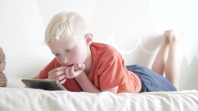 A handsome teenage boy uses a mobile phone at home in bed. 