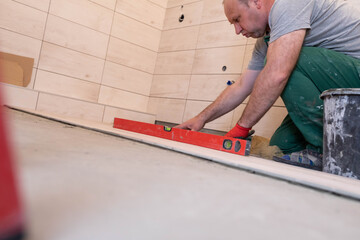 Laying terracotta in the bathroom. Builder during work. Adhesive for ceramic tiles.