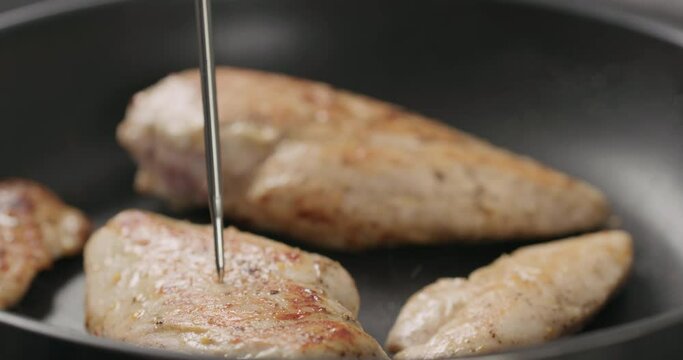 Slow motion check temperature of chicken fillet frying on non stick pan closeup