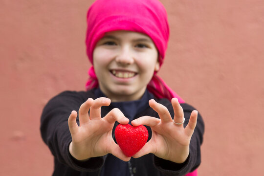 girl with cancer and red heart in the hands
