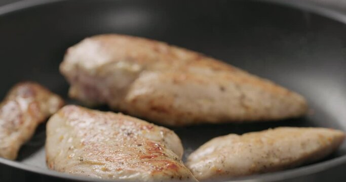 Slow motion check temperature of chicken fillet frying on non stick pan closeup