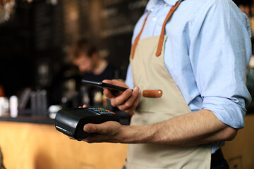 Customer using credit cart for payment to owner at cafe restaurant, cashless technology and credit card payment.