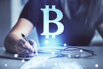 Cryptocurrency hologram over woman's hands writing background. Concept of blockchain. Double...