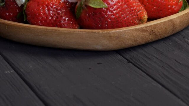 Juicy ripe big red strawberries on an eco bamboo plate on top with whipped cream cloes up view.