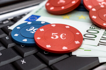 Euro bills and poker chips on laptop keyboard. Online casino.