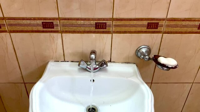 water flowing in modern bathroom sink with faucet