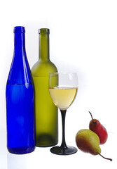 Two bottles, a glass of wine and pears on a white background.