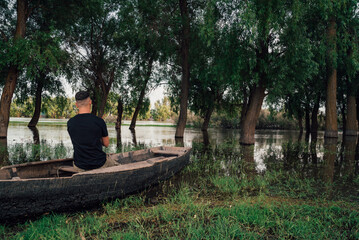 Fisherman is sitting in the old, wooden rowboat and catching the fish on sunny day.